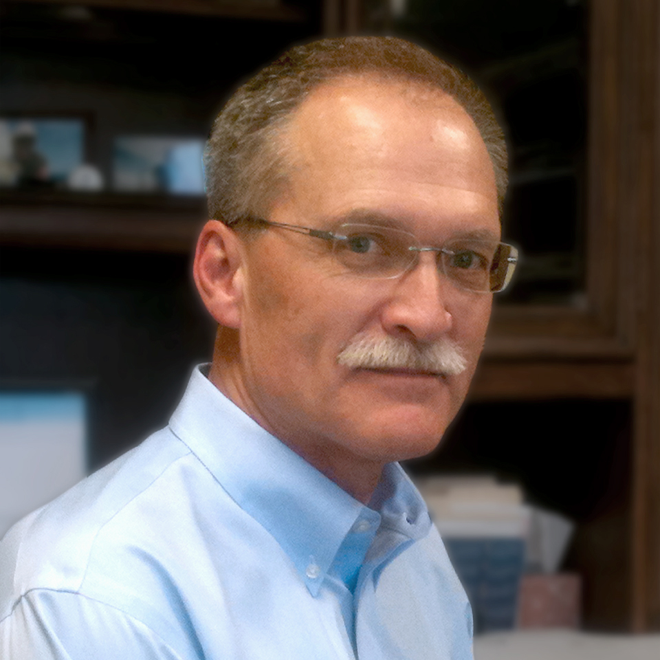 Portrait of Dave McCormack wearing glasses and a light blue shirt.